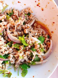 a white plate topped with meat and veggies covered in sauce on top of a table