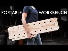 a woman holding a wooden board with holes in it and the words portable workbench