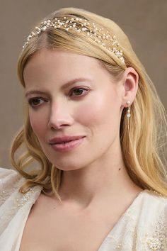 a woman in a white dress wearing a headband with pearls on it's side