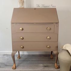 an antique chest of drawers with gold knobs on the top and bottom, sitting in front of a white wall