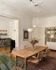 a dining room table with chairs and bookshelves in the background