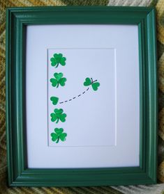 a green frame with four leaf clovers on the side and a string attached to it