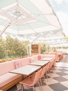 an outdoor seating area with tables and umbrellas on the top floor, lined with checkered tiles