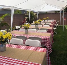 tables with red and white checkered tablecloths are set up under a tent