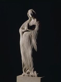 a sculpture of a woman with long hair standing on a pedestal in the dark, holding her hands behind her back