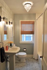 a white toilet sitting next to a sink in a bathroom under a light above a window