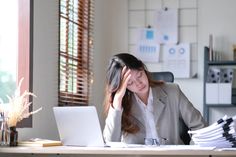 a woman sitting at a desk with her head in her hands