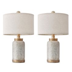 two white and gold table lamps with shades on each lamp, one is turned off