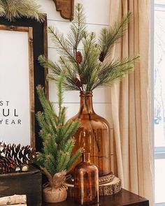 a vase with pine cones and greenery on a table