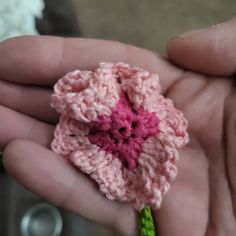 a crocheted flower being held in someone's hand