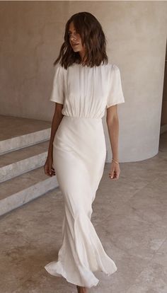 a woman in a white dress walking down some steps with her hand on her hip