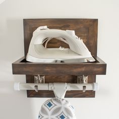 an ironing board mounted on a wall with a wooden shelf holding a white iron