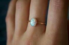 Handmade 8x6mm oval white opal ring✨  * Listing covers just the single opal ring, other rings are sold separately. Dainty and perfect minimalist piece!  Stunning 8x6mm lab grown Kyocera opal gemstones. Each stone is hand set into a bezel and polished for a beautiful shine finish.   Opal means jewel. The energies of this stone will also encourage you to express your true self, in addition to feeling confident and comfortable in your own skin, and this will radiate in your words, thoughts, and actions. * Please note photos are zoomed in up close, therefore the size of the stone may appear slightly larger in photos. Model is wearing a size US 5.5. Please refer to stone measurement to best determine the size & look you're looking for.  Material: 14/20 (karat/purity) gold filled metal OR 925 St Opal Gold Necklace, Minimalist Oval Cabochon Opal Ring, Dainty White Oval Opal Ring, Dainty Handmade Oval Opal Ring, Dainty White Opal Ring For Everyday, Dainty Ethiopian Opal Ring, White Opal Ring, Feeling Confident, Opal White