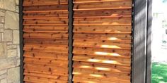 a window covered in wooden slats next to a brick wall