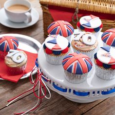 cupcakes decorated in the colors of the british flag on a cake plate with red, white and blue decorations