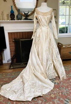 an antique wedding dress on display in front of a fireplace