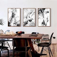 three black and white paintings on the wall above a dining room table