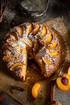 a cake that is sitting on top of a cutting board next to sliced peaches