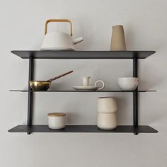 three shelves with cups, teapots and other items on them against a white wall