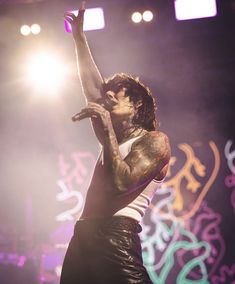 a man with tattoos on his arm and arms up in the air while holding a microphone