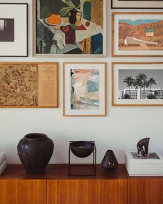 there are many pictures on the wall with vases and other items in front of them