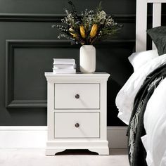 a white nightstand sitting next to a bed in a bedroom