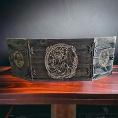 two wooden boxes sitting on top of a table next to each other, one with an image of a dragon in the middle