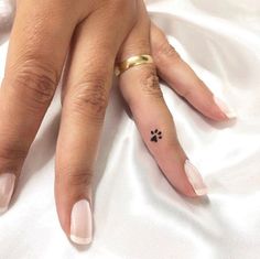 a woman's hand with a small black dog paw tattoo on her left thumb