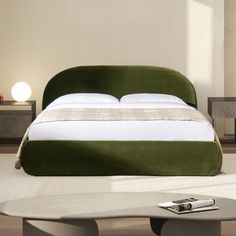 a green bed sitting in the middle of a room next to a table and chair