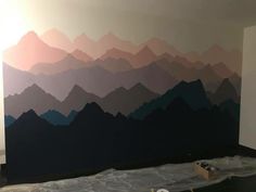 a wall with mountains painted on it in a room that is being renovated and remodeled