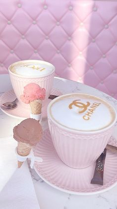 an ice cream sundae sits on a pink plate next to two cupcakes