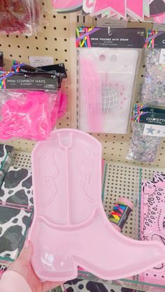 a person holding a pink cowboy boot shaped object in front of other items on a store shelf