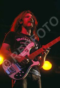 a man with long hair playing an electric guitar on stage at a music festival or concert