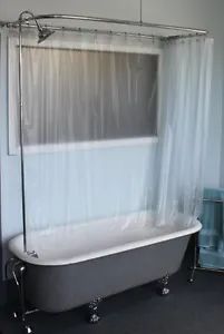 a bath tub sitting next to a toilet in a bathroom under a window with white curtains