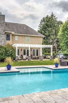 a house with a pool in front of it and a covered patio next to it