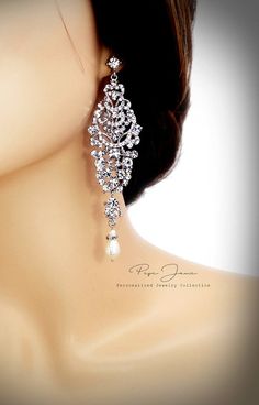 a close up of a woman's head wearing earrings with pearls and crystals on it