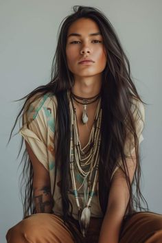 a woman with long hair sitting on the ground wearing jewelry and looking at the camera