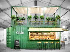 an outdoor cafe with green walls and plants on the roof, along with tables and chairs