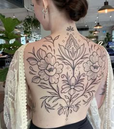 the back of a woman's upper body with flowers on her left and right side