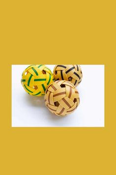 three wooden balls sitting next to each other on a white surface with yellow and green stripes