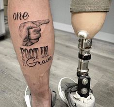 a person standing next to a foot with a tattoo on it's leg and the words one foot in grave