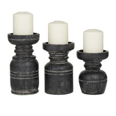 three black candle holders with white candles in them