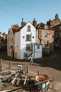 a man walking down the street in front of a white building with a boat on it