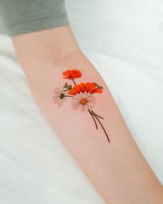 a woman's arm with three red flowers on it