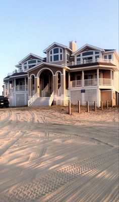 a large house sitting on top of a sandy beach next to a white truck parked in front of it