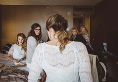 a group of women standing around each other in front of a bed with sheets on it