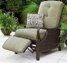 a chair and ottoman sitting on a patio with plants in the backgroung