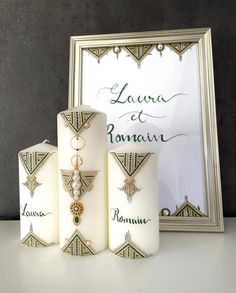 three white candles sitting next to a framed photo