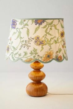 a lamp that is sitting on top of a wooden base and has flowers on it