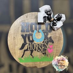 a wooden sign that says hold your horses on it with a bow in the middle